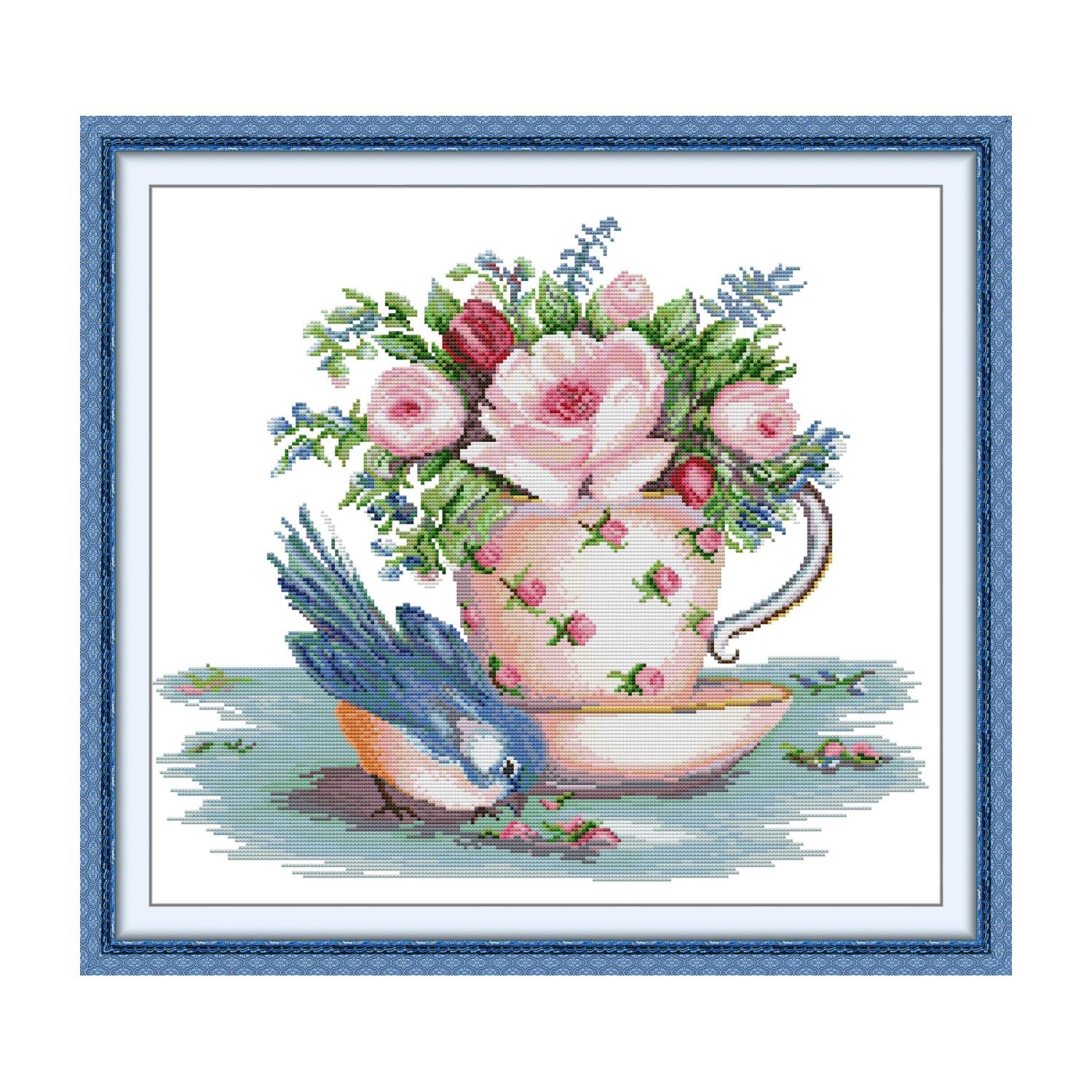 Bird cross stitch design of a blue bird beside a pink rose teacup and saucer