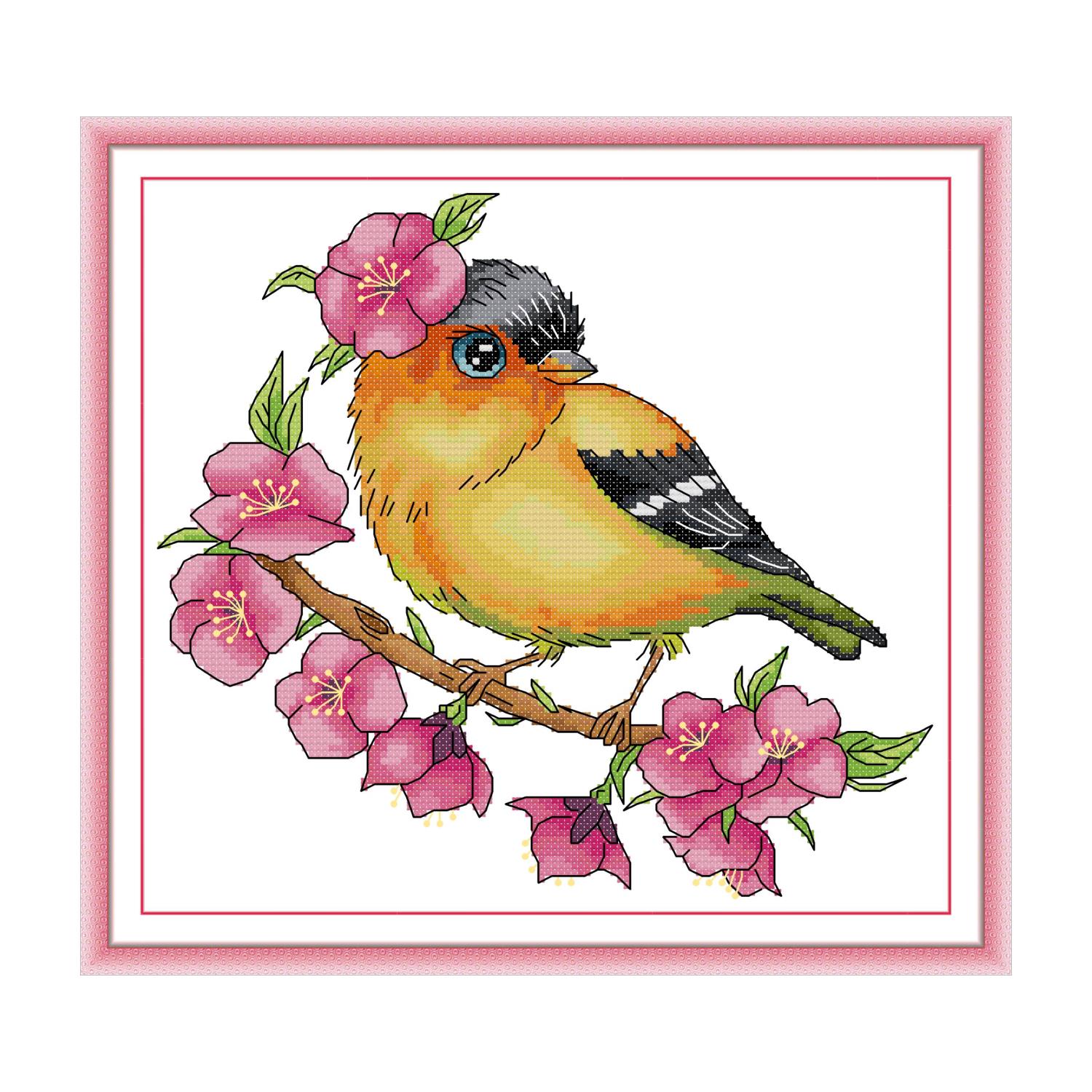 Bird cross stitch kit with pink cherry blossom branch framed in a cozy reading nook