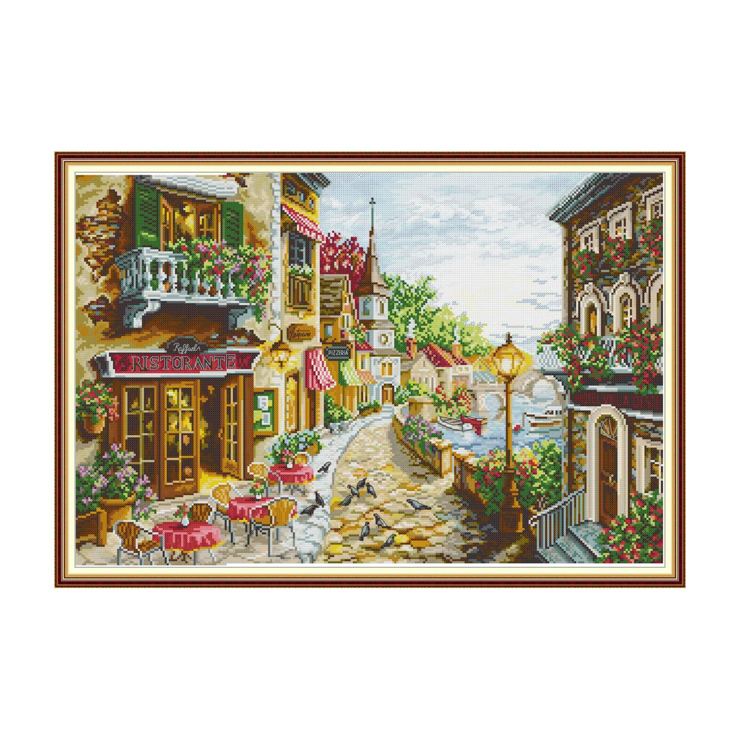 Landscape cross stitch design of a European street cafe with flower-decorated balconies and a cobblestone path