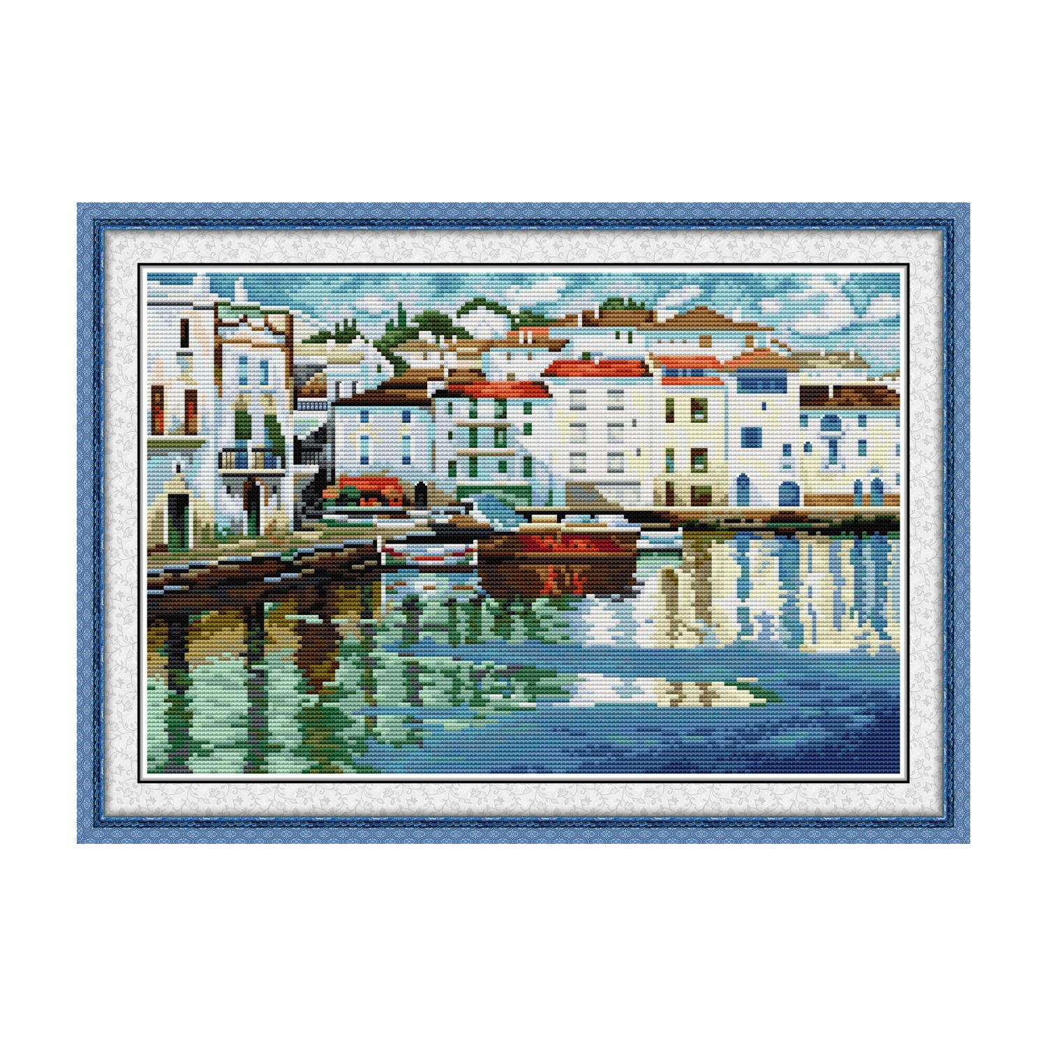 Landscape cross stitch design of a quiet harbor bay with colorful buildings, wooden piers, and boats reflected in calm water